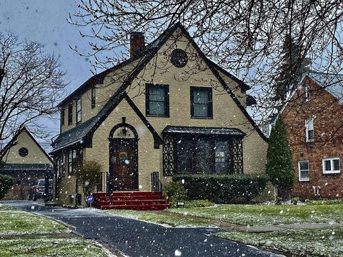 Tudor-style two-story house with a steep gabled front during a light snowfall